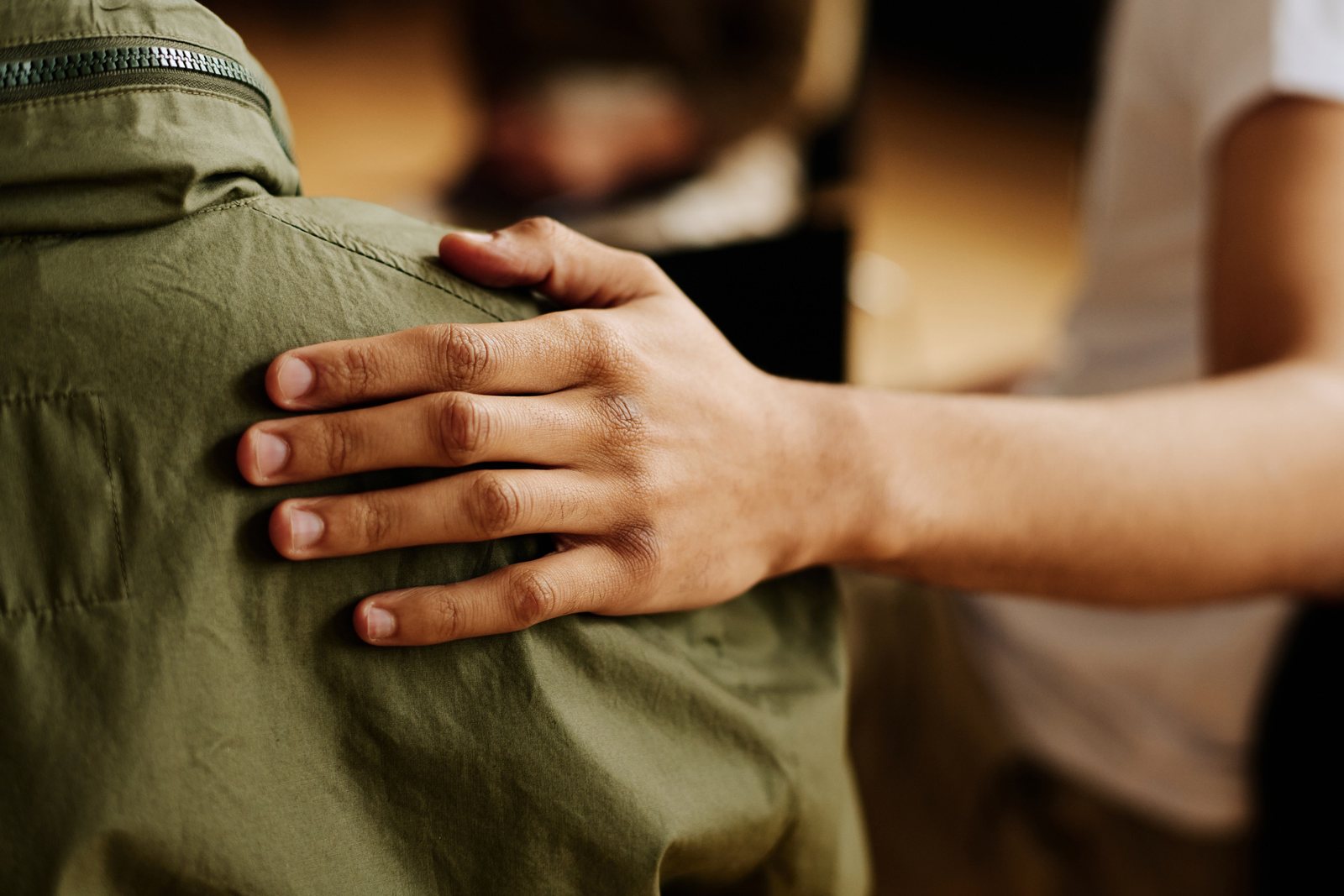 A hand resting on a young person’s shoulder